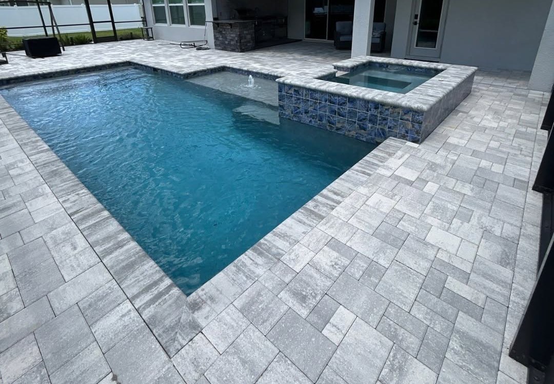 Pavers surrounding a swimming pool and raised spa.