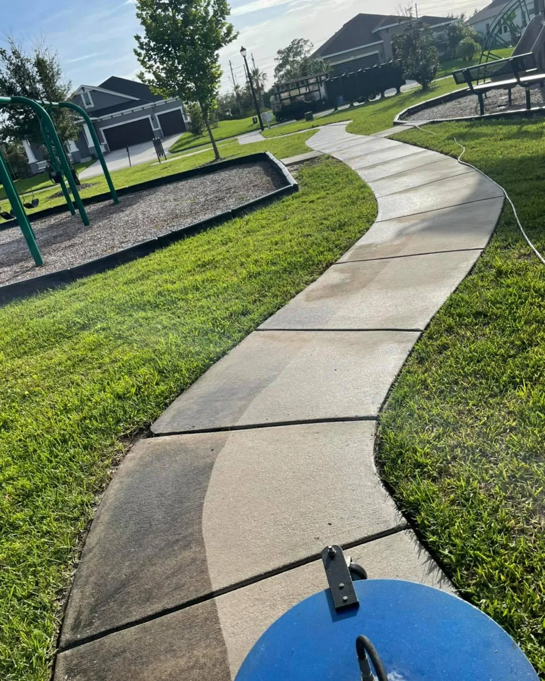 Key Vista HOA common-area sidewalk mid-clean: dirty concrete in front, cleaned behind